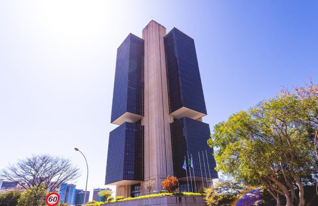 Edifício do Banco Central do Brasil em Brasília, com centro de concreto e blocos escuros, sob céu azul.