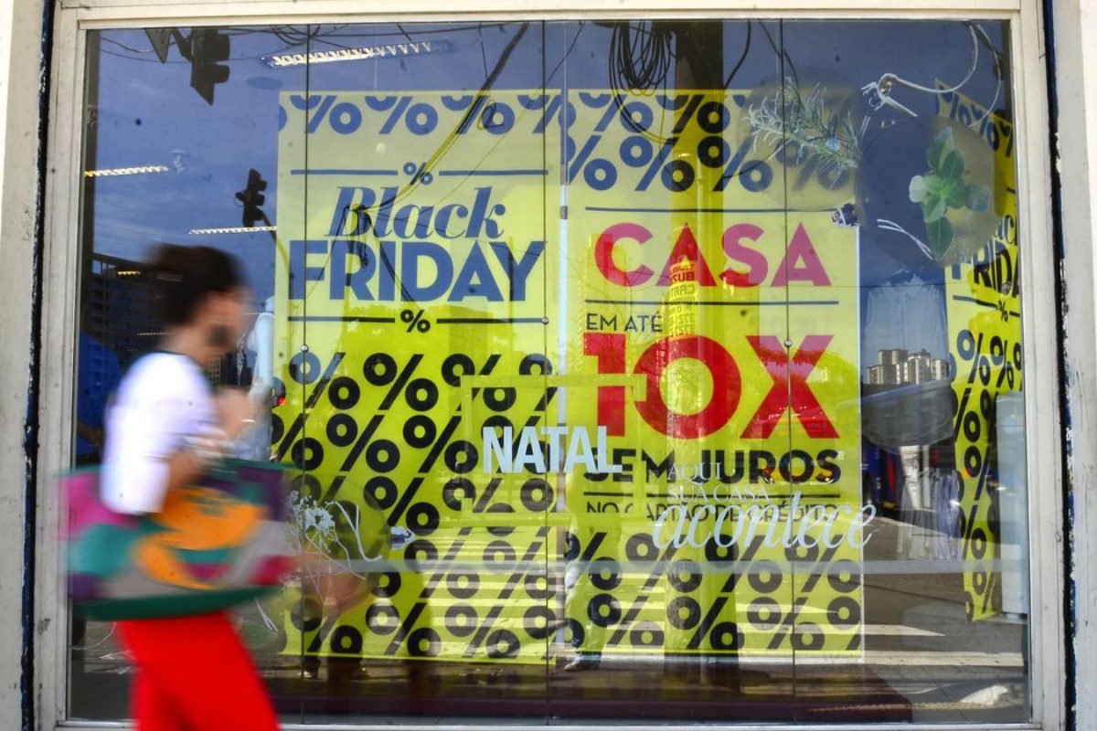 imagem de pessoa andando na rua em frente à loja com escrita "black friday", "casa" e "em até 10x sem juros", ilustrando o tema "black friday"