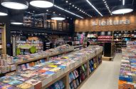 Livraria moderna e iluminada com mesas e prateleiras cheias de livros à venda.