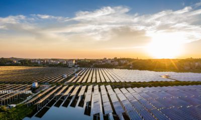 Extensa usina solar flutuante ao pôr do sol, com painéis e reflexos dourados na água.