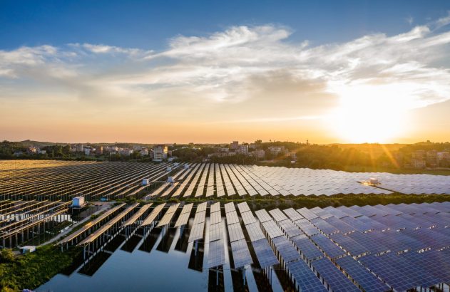 Extensa usina solar flutuante ao pôr do sol, com painéis e reflexos dourados na água.