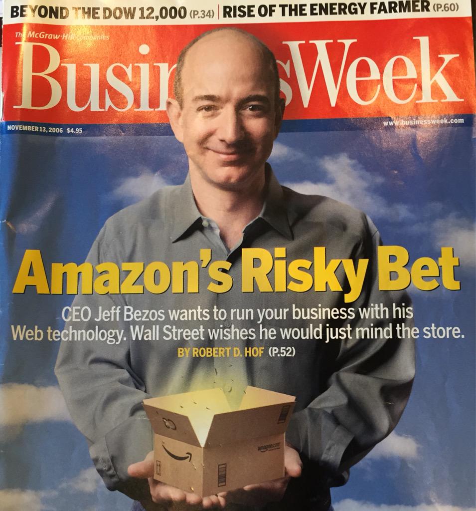 Jeff Bezos sorrindo, segurando uma caixa aberta da Amazon com luz emanando. Capa de revista (2006).