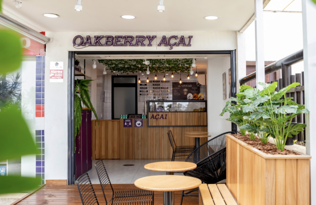 Fachada da loja Oakberry Açaí com entrada e mesas ao ar livre.