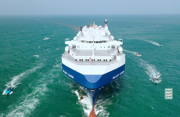 Grande navio Galaxy Leader azul e branco no mar, rodeado por lanchas menores.