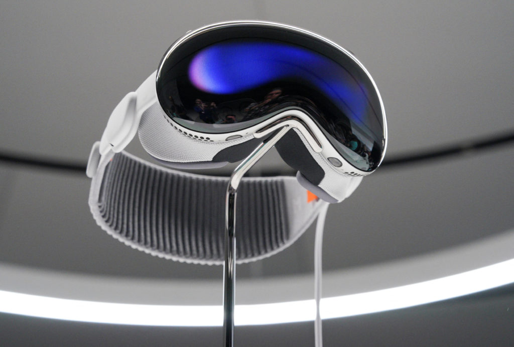 Um headset VR/AR branco e prateado com visor espelhado azul, em exposição.