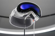 Um headset VR/AR branco e prateado com visor espelhado azul, em exposição.