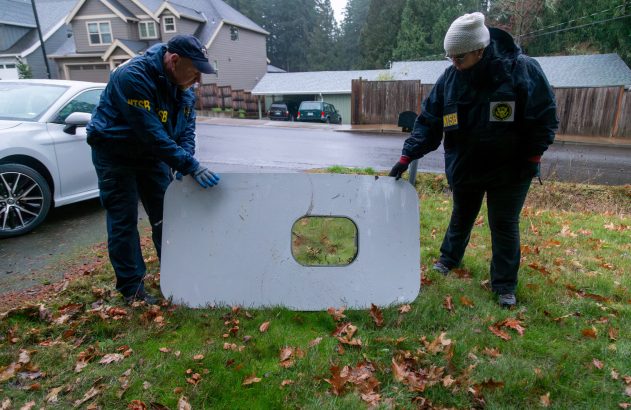 Dois investigadores movem peça de aeronave com recorte em área residencial.