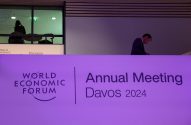 Banner do Fórum Econômico Mundial Davos 2024 com homem de terno em pé acima e outras pessoas ao fundo.
