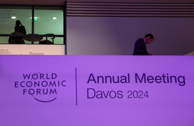 Banner do Fórum Econômico Mundial Davos 2024 com homem de terno em pé acima e outras pessoas ao fundo.