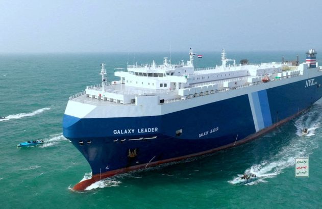 Navio 'Galaxy Leader' no mar, cercado por botes. Bandeira do Iêmen no mastro. Captura do cargueiro.