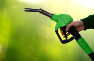 Mão segura bico de abastecimento verde com logo 'BIO' (folha), em fundo verde.