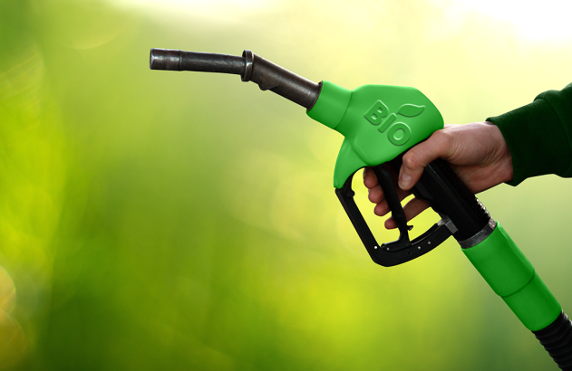 Mão segura bico de abastecimento verde com logo 'BIO' (folha), em fundo verde.