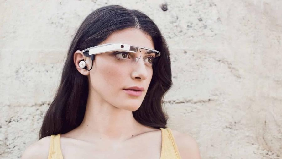 Mulher usando Google Glass e fone de ouvido, olhando para o lado.