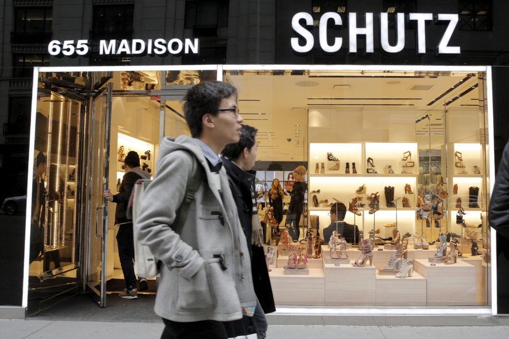 Pessoas passam em frente à loja Schutz (655 Madison) com sapatos expostos na vitrine.