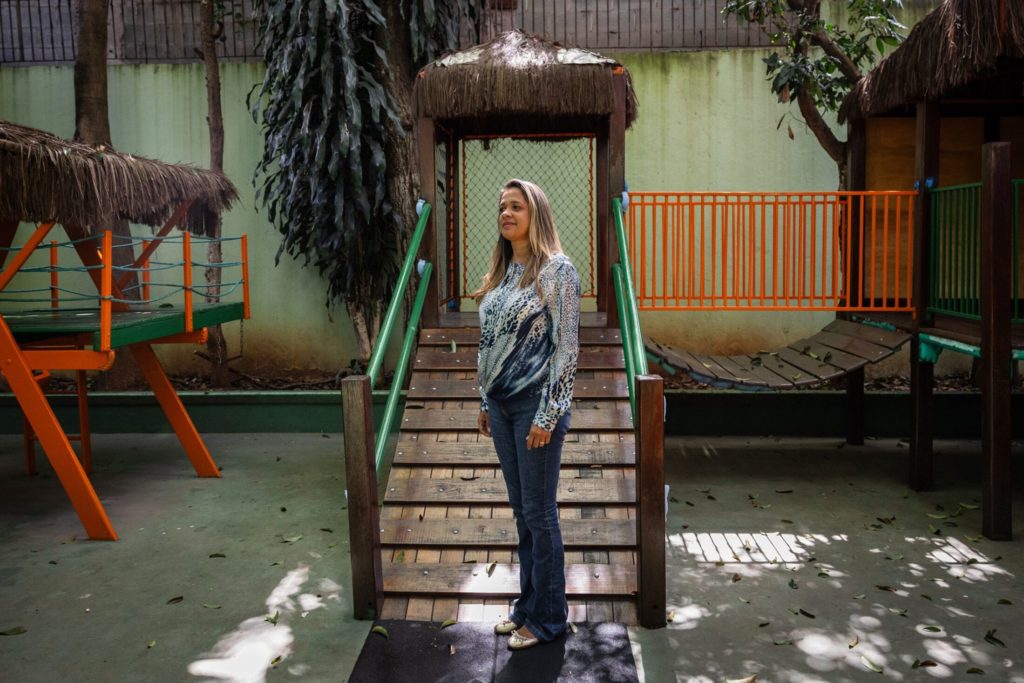 Mulher em pé em escadas de madeira de um parquinho, olhando para cima.