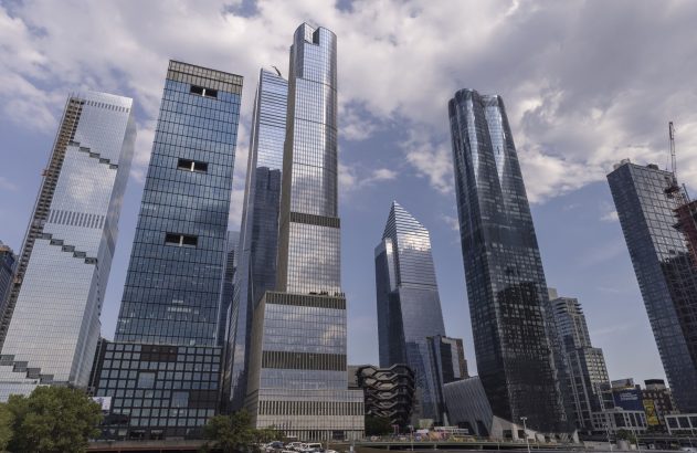 Arranha-céus modernos de vidro refletem o céu nublado em uma paisagem urbana.
