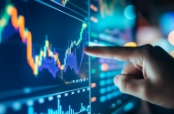 Mão apontando para gráficos de mercado financeiro em uma tela digital.