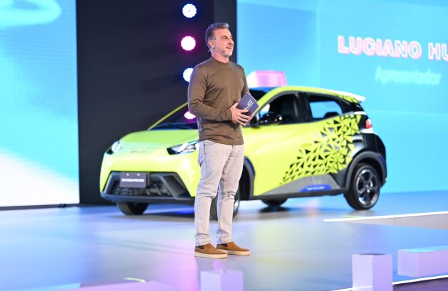 Homem em palco apresenta carro elétrico verde-limão em evento de lançamento.