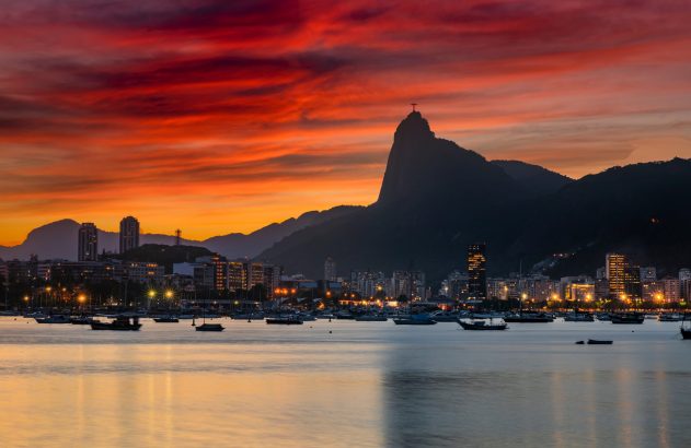 Pôr do sol no Rio de Janeiro: Corcovado, Baía de Guanabara e barcos sob um céu vibrante.