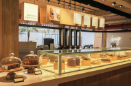 Interior de confeitaria Dengo com vitrine de doces, balcão de atendimento e equipamentos de café.