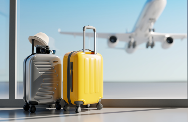 Duas malas de viagem, uma com chapéu e câmera, em janela de aeroporto com avião decolando ao fundo.