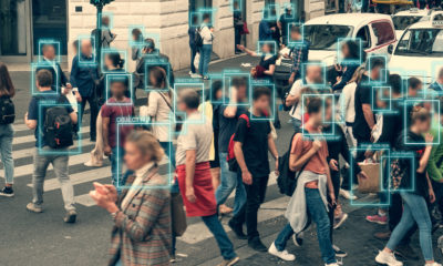 Multidão cruzando faixa de pedestres com caixas de detecção e dados de IA sobrepostos.