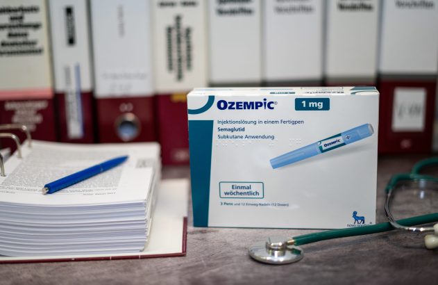 Caixa de Ozempic 1mg, estetoscópio e pasta de documentos em mesa.