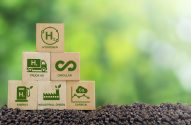 Blocos de madeira empilhados no solo com ícones de hidrogênio, transporte e energia verde, economia circular e redução de carbono.