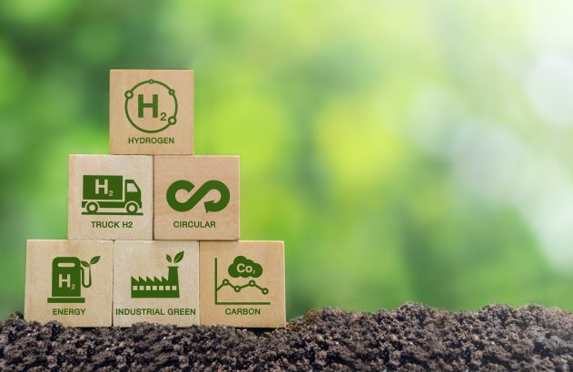Blocos de madeira empilhados no solo com ícones de hidrogênio, transporte e energia verde, economia circular e redução de carbono.
