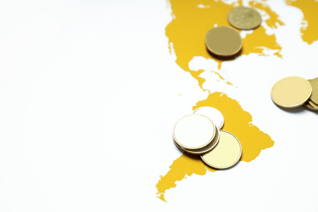 Moedas douradas genéricas sobre um mapa amarelo das Américas.
