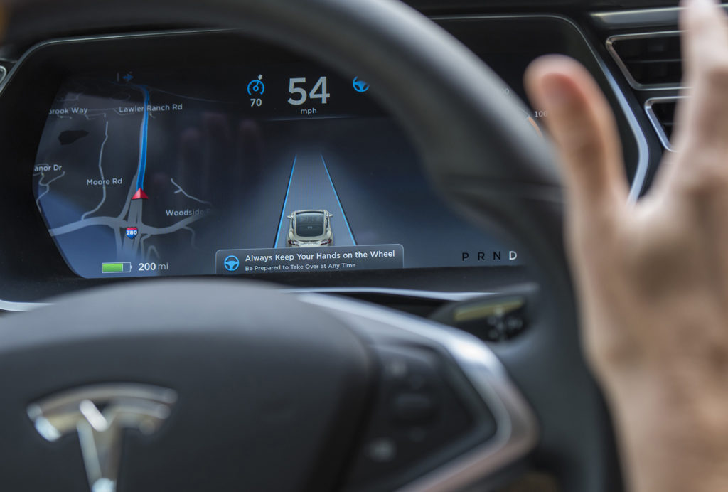 Mão fora do volante em carro com painel digital exibindo navegação, velocidade 54 e veículo em faixa.