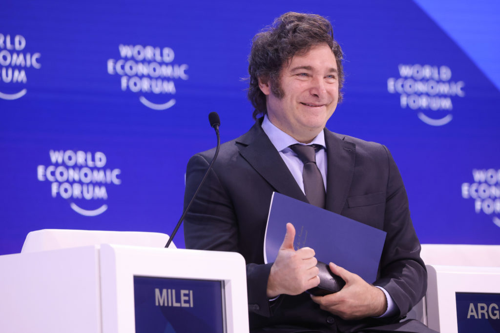 Javier Milei sorrindo e fazendo joinha em pódio do Fórum Econômico Mundial.