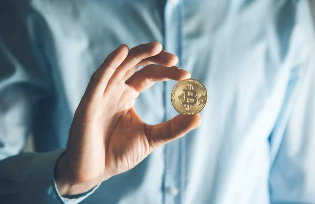 Homem segurando moeda de bitcoin