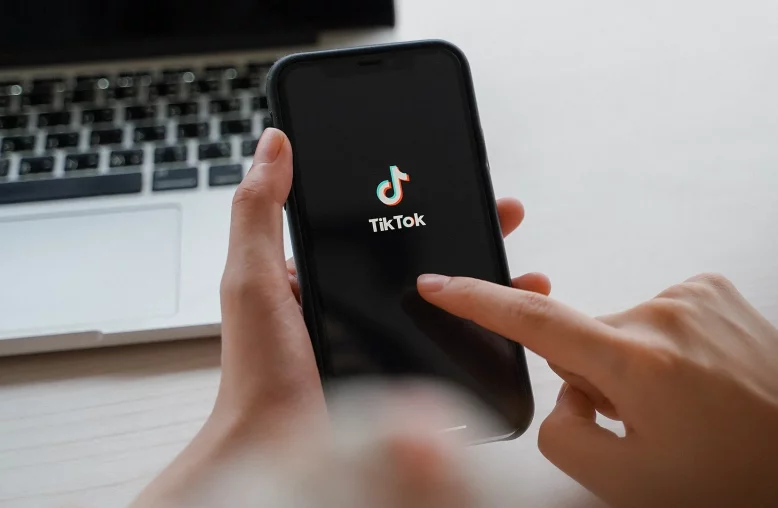 Pessoa manuseia um celular que exibe o logo do TikTok