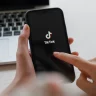 Pessoa manuseia um celular que exibe o logo do TikTok