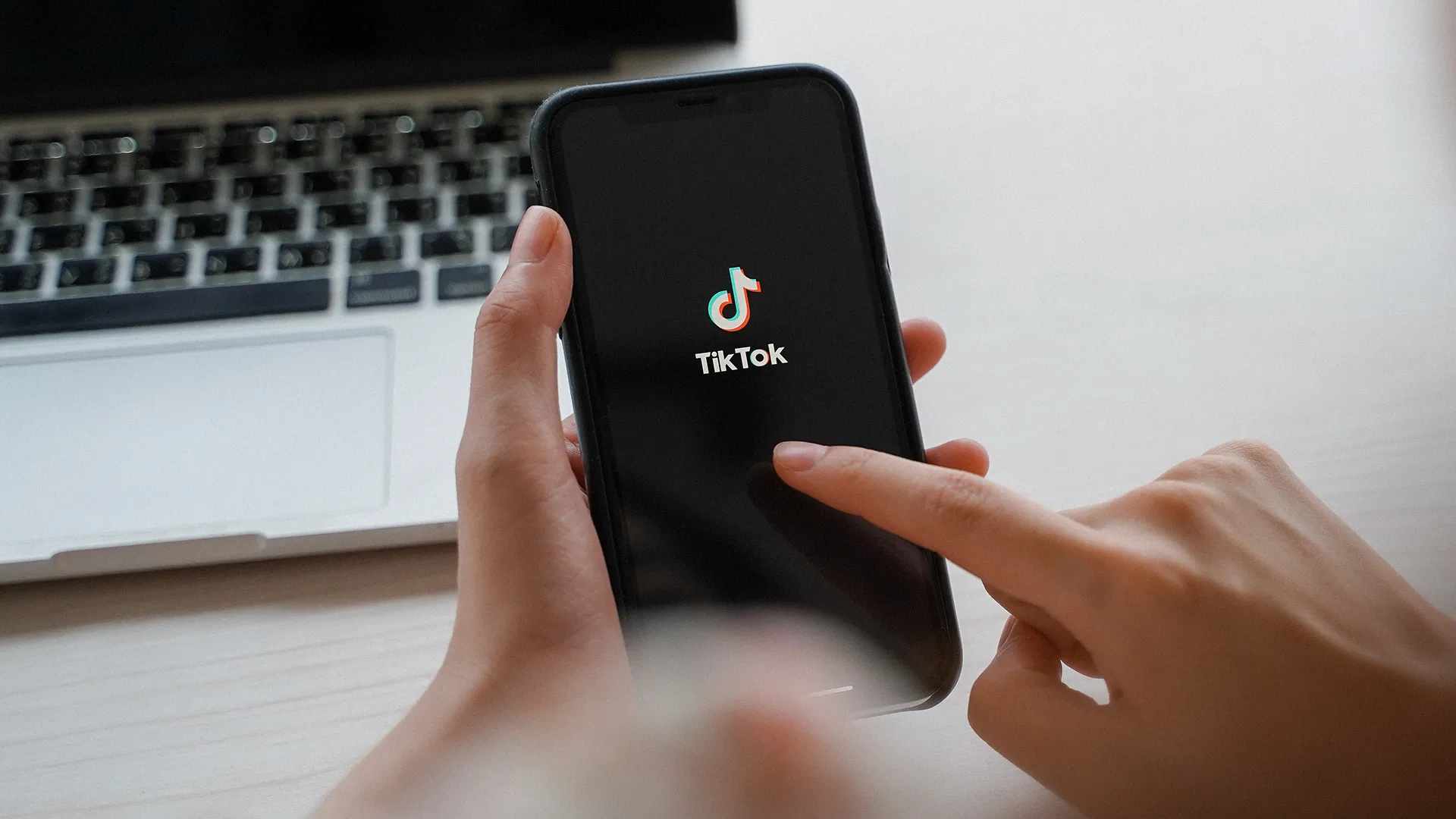 Pessoa manuseia um celular que exibe o logo do TikTok