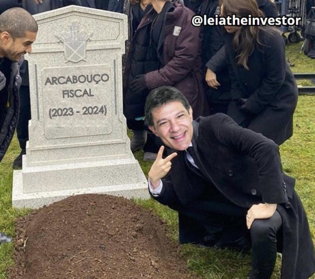 Haddad sorri e faz sinal de paz junto a lápide "Arcabouço Fiscal (2023-2024)" e cova.