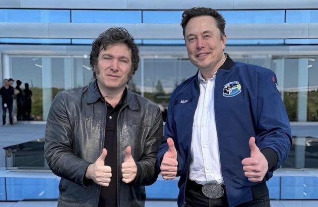 Elon Musk e Javier Milei sorrindo e fazendo sinal de positivo em frente a um prédio moderno.