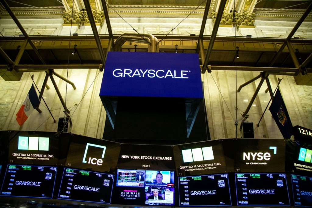 Interior da Bolsa de NY com telões exibindo o logo Grayscale, dados financeiros de GBTC e informações da NYSE.