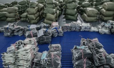 Inúmeros sacos empilhados e produtos embalados, alguns da SHEIN, em um centro de distribuição.