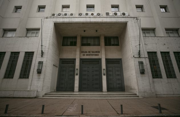 Fachada cinza do edifício da Bolsa de Valores de Montevidéu, com grande porta central e letreiro.