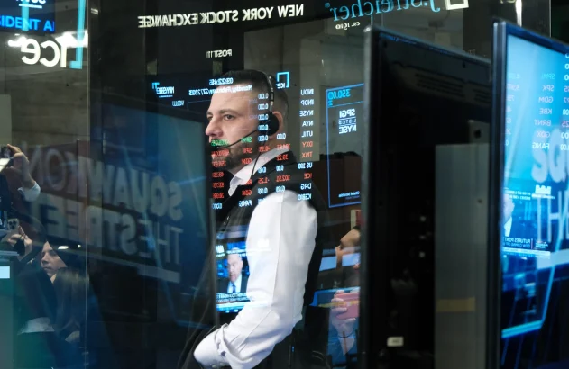 Foto de um homem de camisa social branca, atrás de um vidro com gráficos