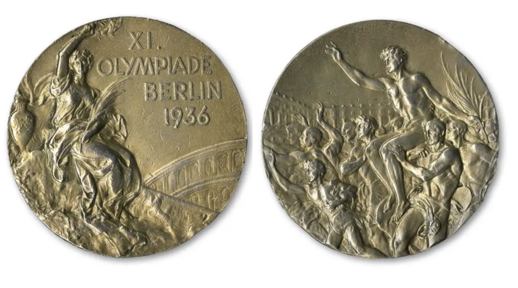 Medalha Olímpica de Berlim 1936. Um lado mostra figura feminina, o outro, atletas masculinos celebrando a vitória.
