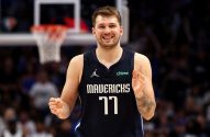 Luka Dončić, jogador de basquete, sorri para a câmera em quadra, vestindo a camisa 77 do Mavericks.
