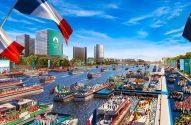 Abertura Olímpica Paris 2024: desfile de barcos no rio, pessoas nas margens e bandeiras nacionais.