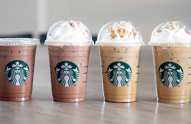 Quatro bebidas Starbucks geladas em copos plásticos: duas de chocolate e duas de café, algumas com chantilly.