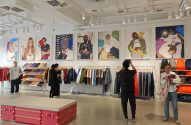Loja da marca Supreme. Clientes navegam entre roupas expostas em araras e grandes pôsteres com a marca.