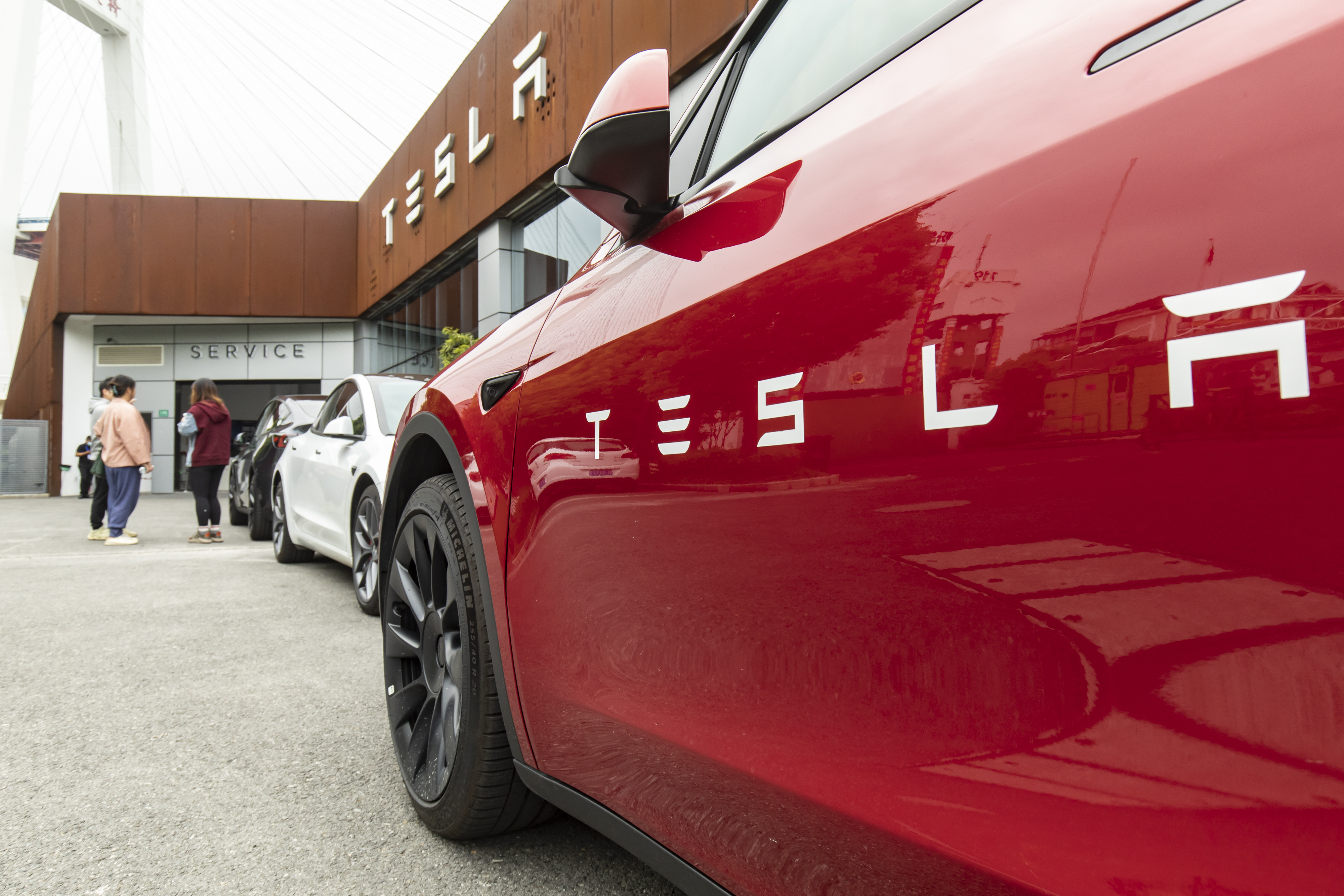 Carro vermelho com o logotipo da Tesla, fotografado de lado