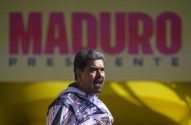 Nicolás Maduro discursa, com a boca aberta, à frente de um painel amarelo com "MADURO" em rosa e "PRESIDENTE" abaixo.