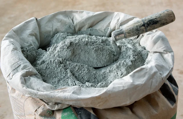 Pó de cimento e espátula colocados em embalagem de saco